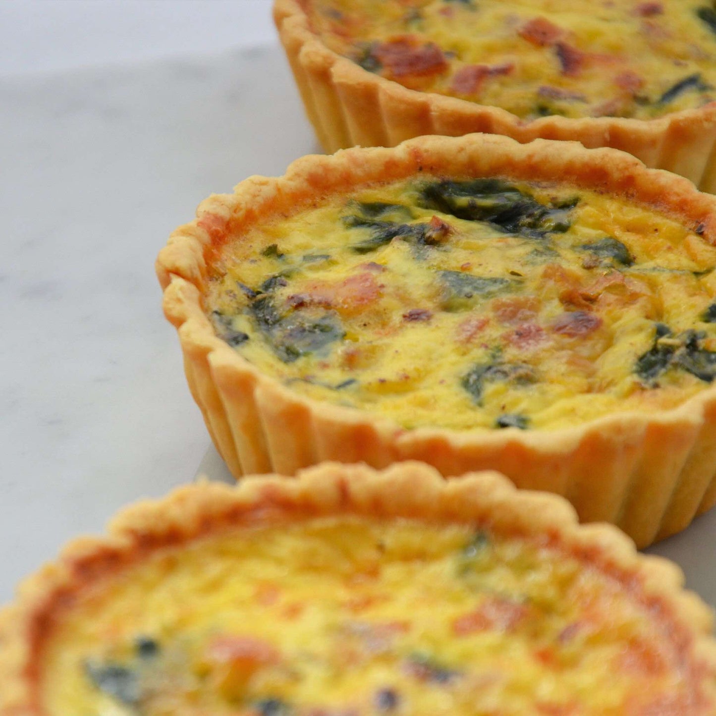 Fresh baby spinach, premium bacon strips and cheeses in an aromatic light custard, set in our signature thin crust. This is a 10cm quiche.